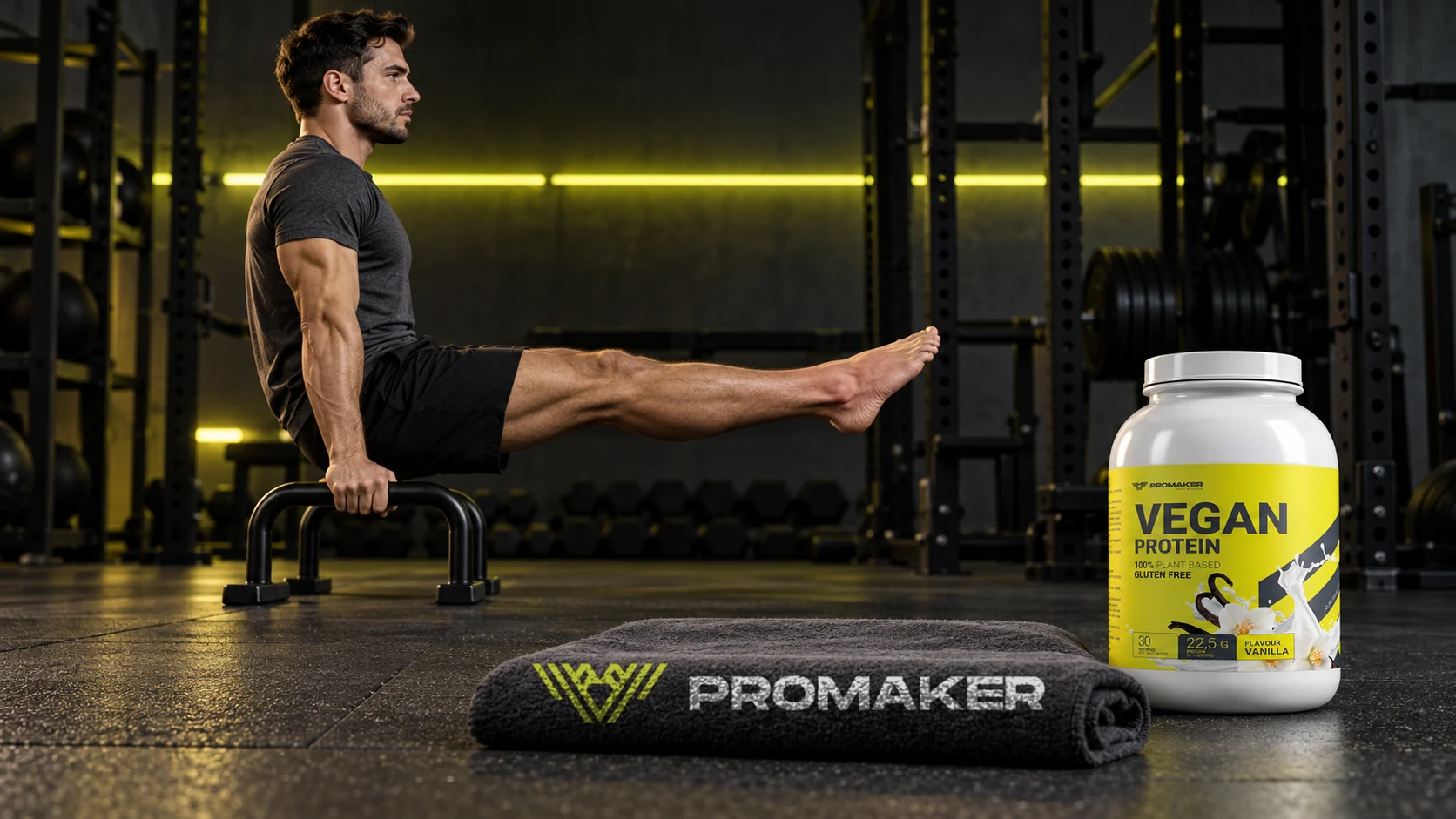 Mężczyzna w L-sit na poręczach w siłowni, obok odżywka Vegan Protein PROMAKER i ręcznik z logo