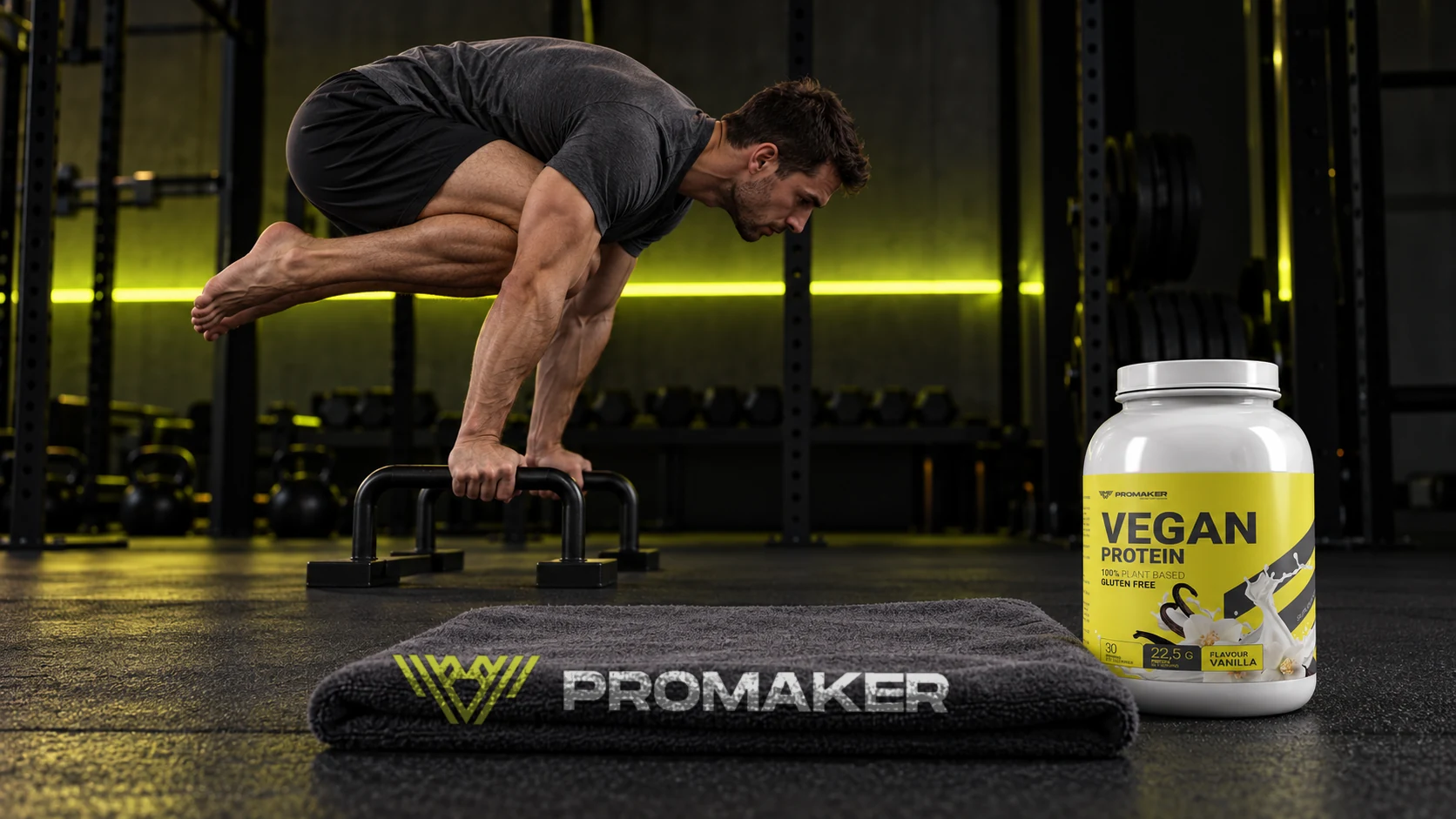 Mężczyzna w tuck planche na poręczach w siłowni, obok odżywka Vegan Protein PROMAKER i ręcznik z logo